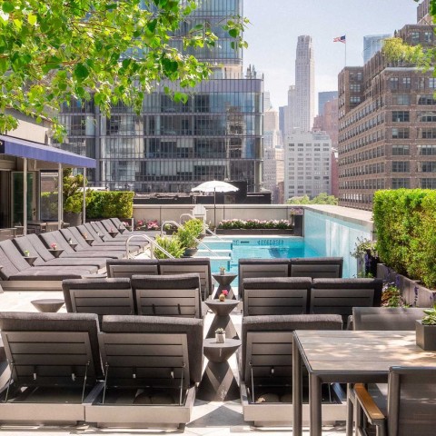 a pool with chairs and tables on a rooftop