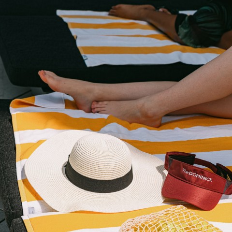 a person's legs and a hat on a beach towel