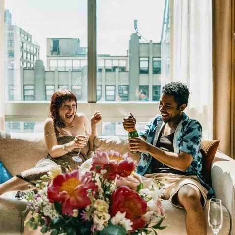 a man and woman sitting on a couch with flowers in front of them