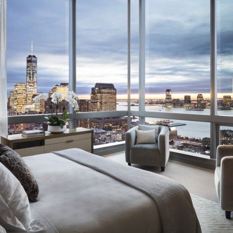 a bedroom with a view of a city and a large window