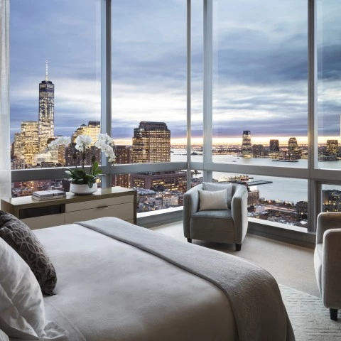 a bedroom with a view of a city and a large window