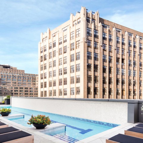 a pool with chairs and a building in the background