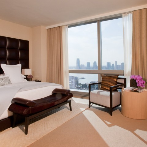 a bedroom with a large window overlooking a city