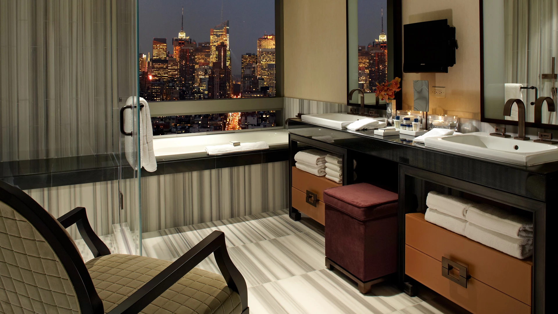 A luxurious bathroom with a soaking tub, double vanity, and city view