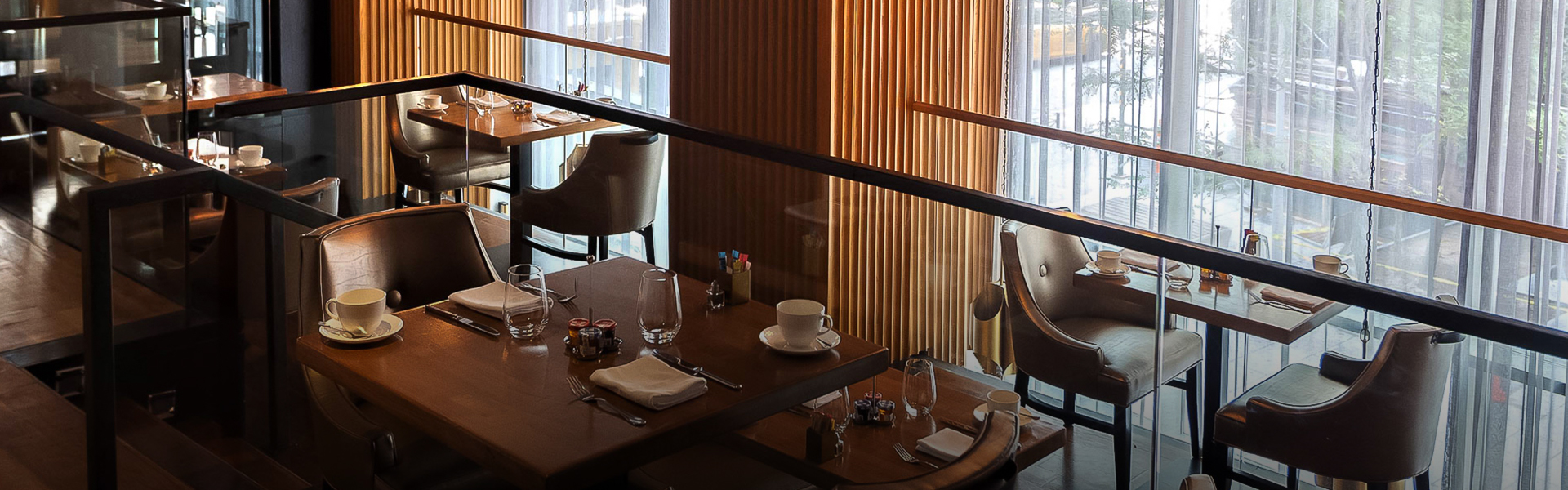 A dining area with tables and chairs, a glass railing, and wooden decor.