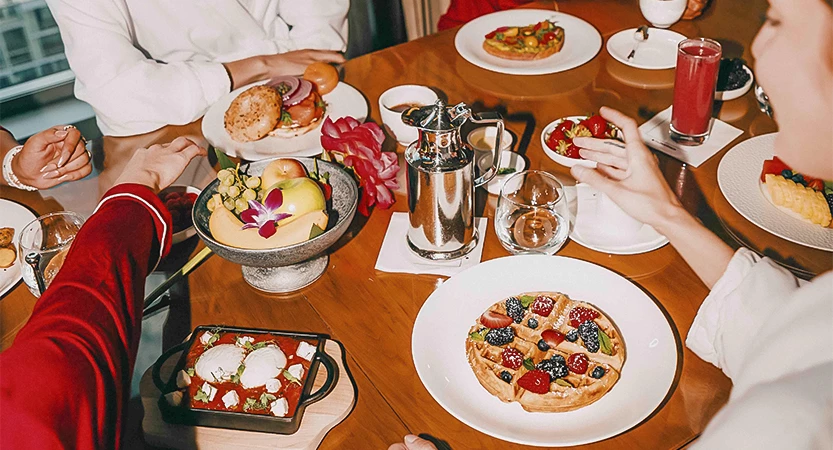 A table set with various breakfast dishes and people eating.