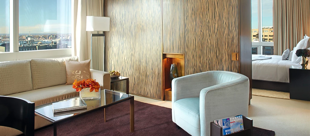 A luxurious hotel room with a sofa, armchair, coffee table, and city view.
