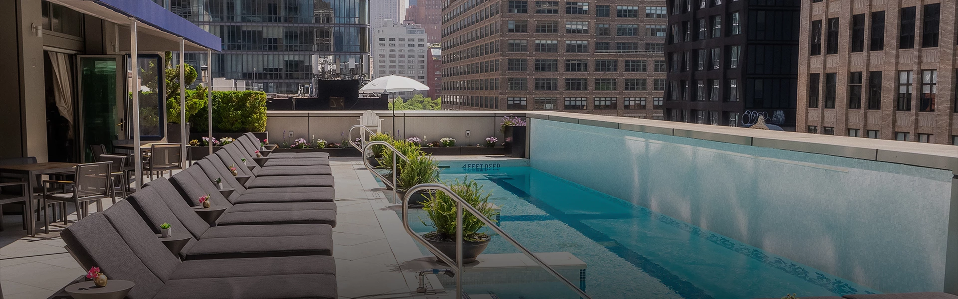 A rooftop pool with lounge chairs and a city skyline view.
