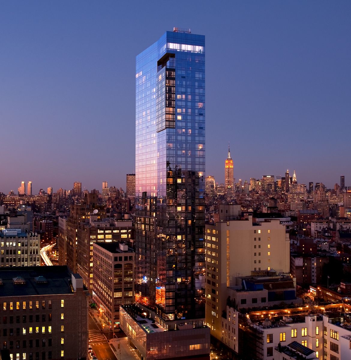 A tall glass building in a city at evening