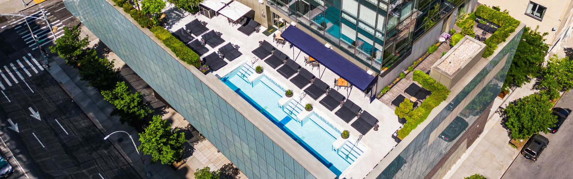Aerial view of a rooftop pool with lounge chairs and umbrellas.
