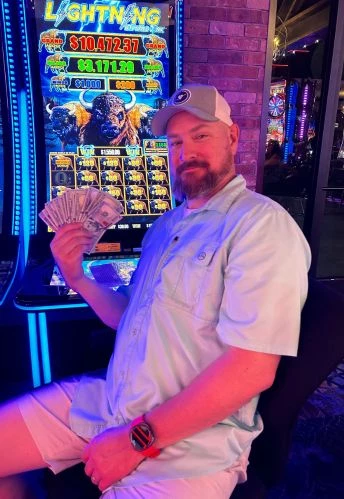 a man holding money in front of a slot machine