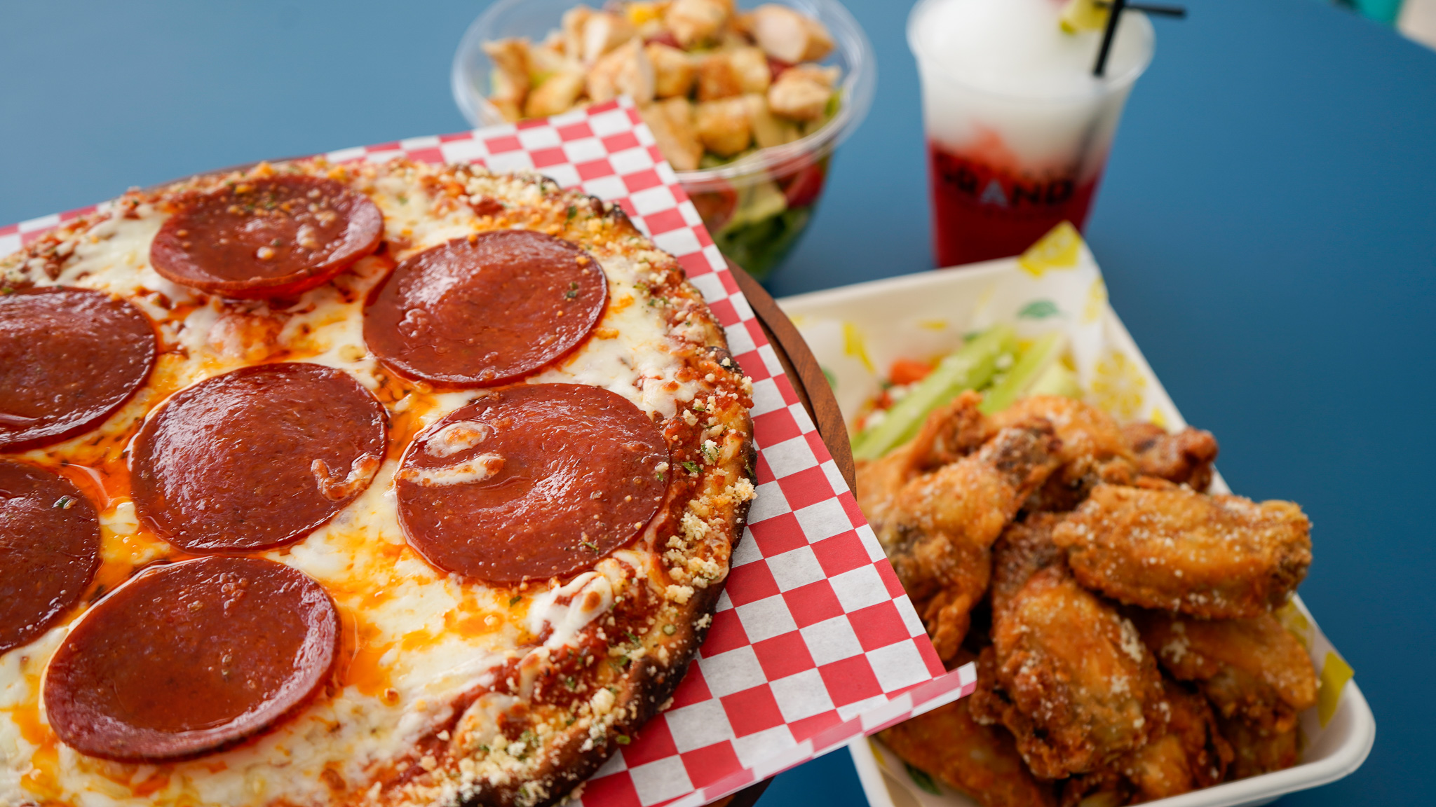 a pizza with chicken wings and a drink