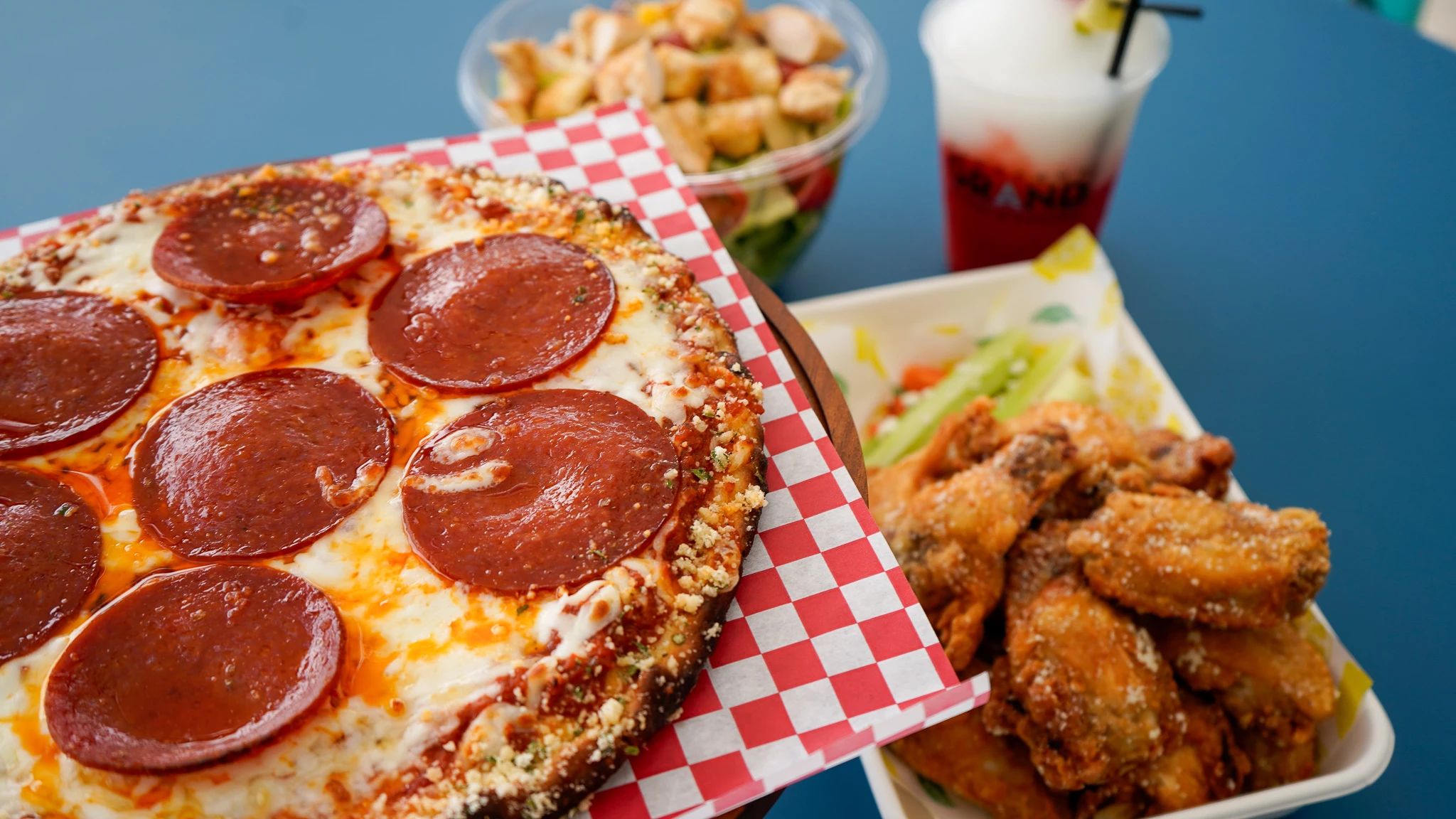 a pizza with chicken wings and a drink