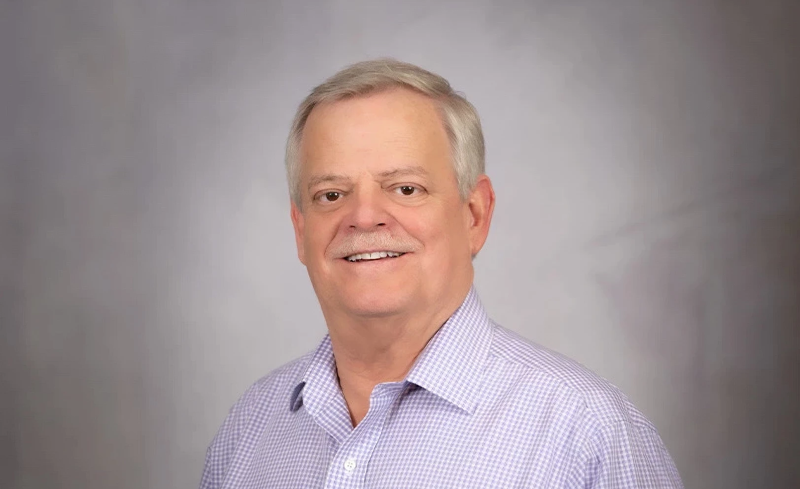 a man with a mustache wearing a purple and white checkered shirt