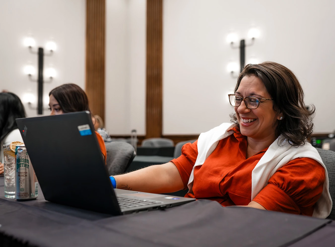 a woman smiling at a laptop