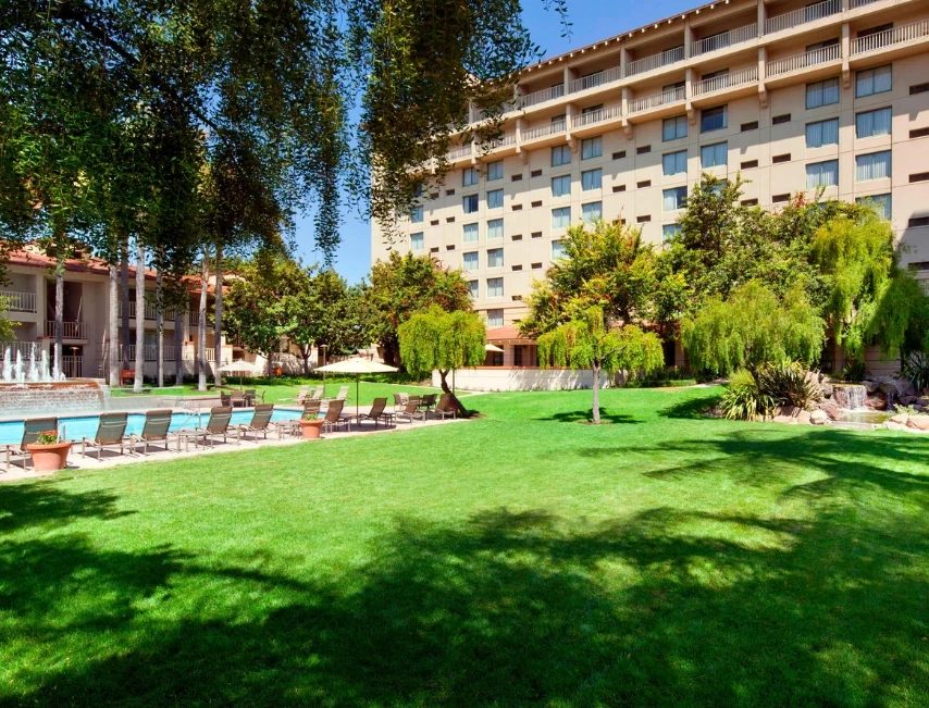 a lawn with chairs and trees in front of a building