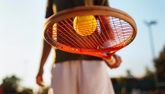 man balancing tennis ball on racket