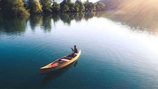 some canoeing through a lake during sun set