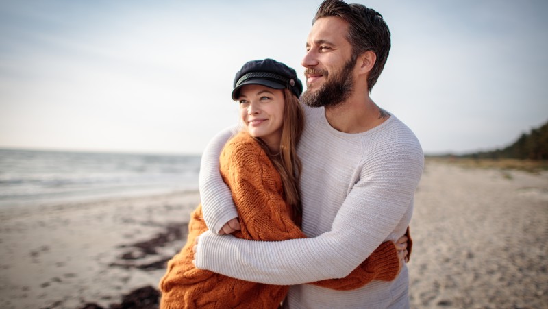 a man and woman hugging on a beach