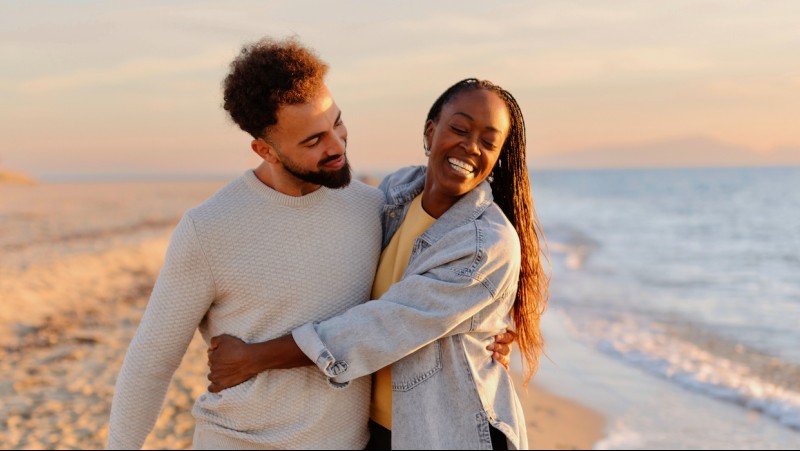 a man and woman hugging on a beach