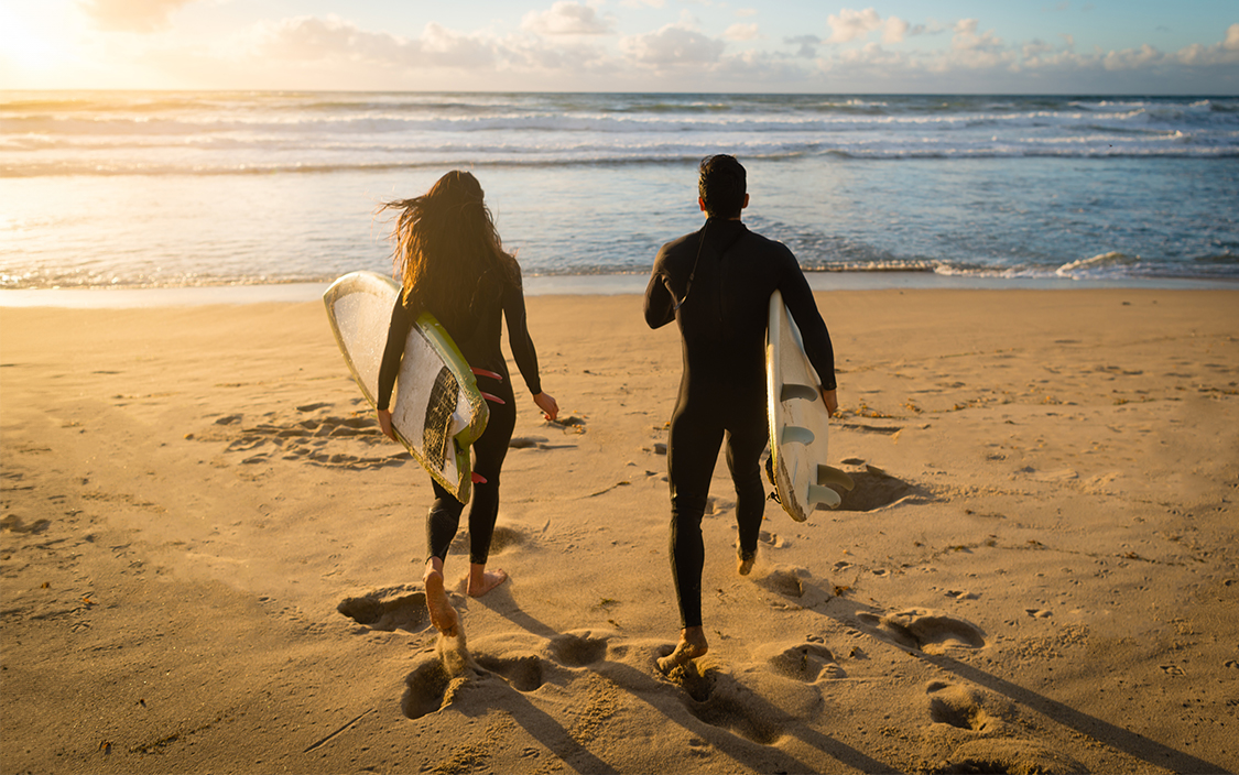 a man and woman holding surfboards on a beach