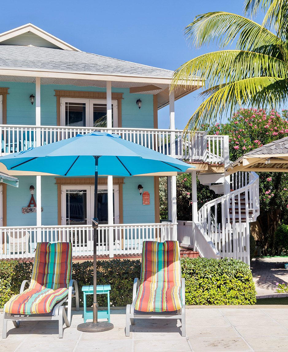 a two chairs and a blue umbrella in front of a house