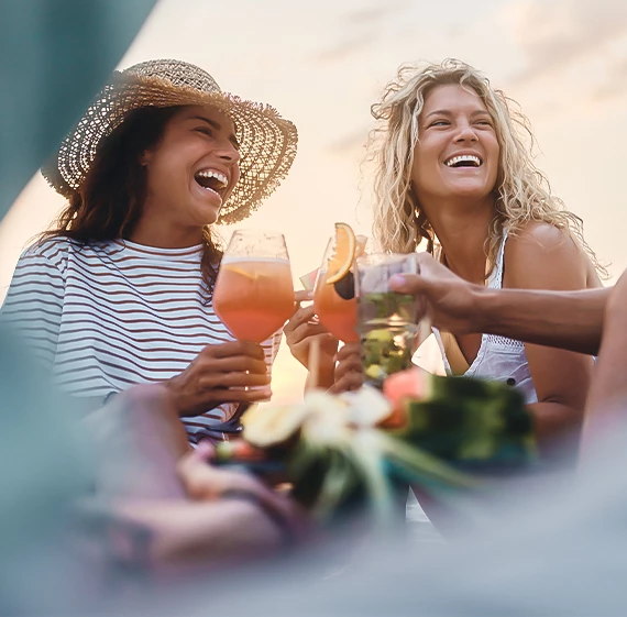a group of women laughing and holding drinks