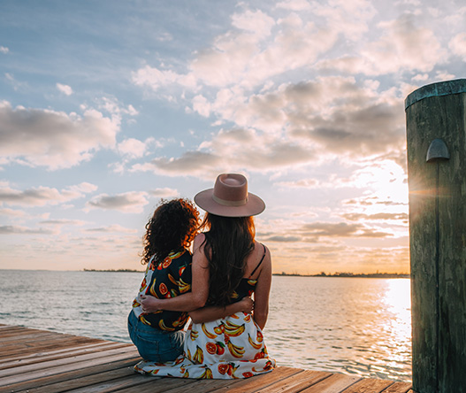 two women sitting on a dock looking at the water