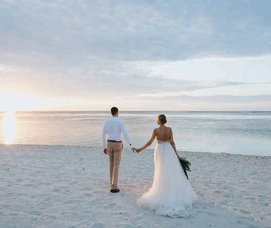a man and woman holding hands on a beach