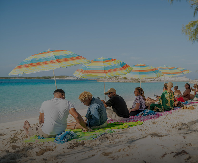 a group of people sitting on the beach with umbrellas