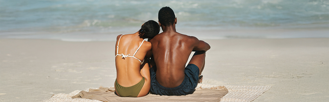 a man and woman sitting on the beach