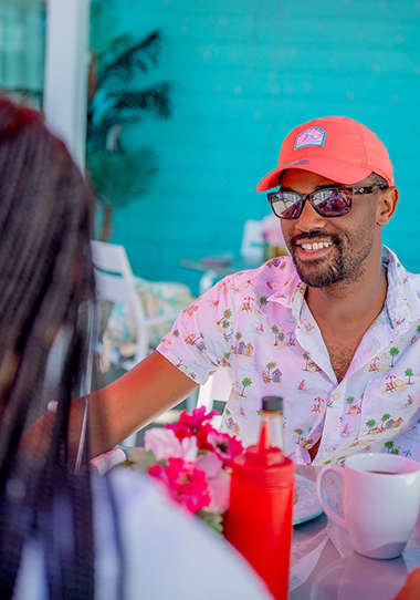 a man wearing sunglasses and a hat sitting at a table with a woman