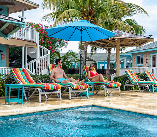 a man and woman sitting on lounge chairs by a pool