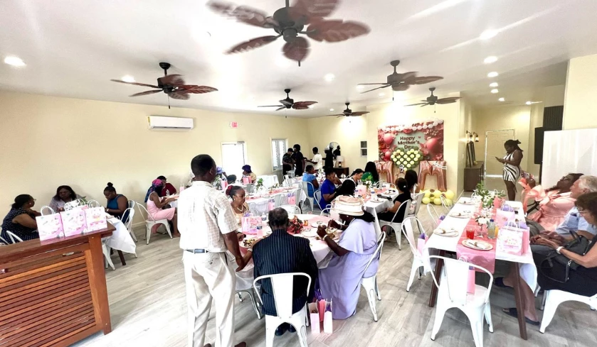 a group of people at tables in a room with fans