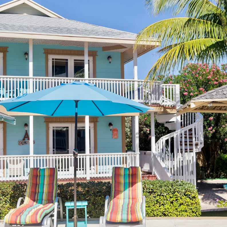 two chairs and umbrellas outside of a house