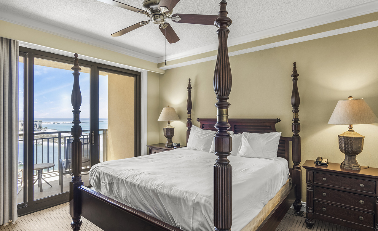 a bed with a ceiling fan and a glass door