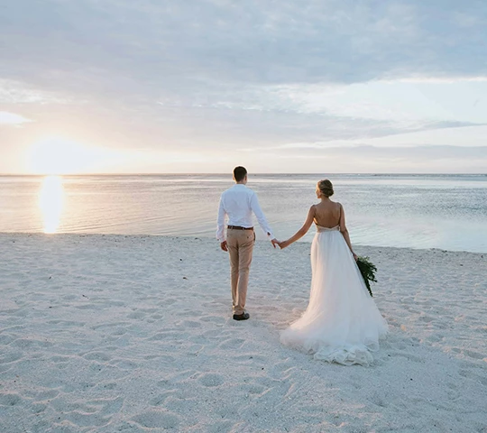 a man and woman holding hands on a beach