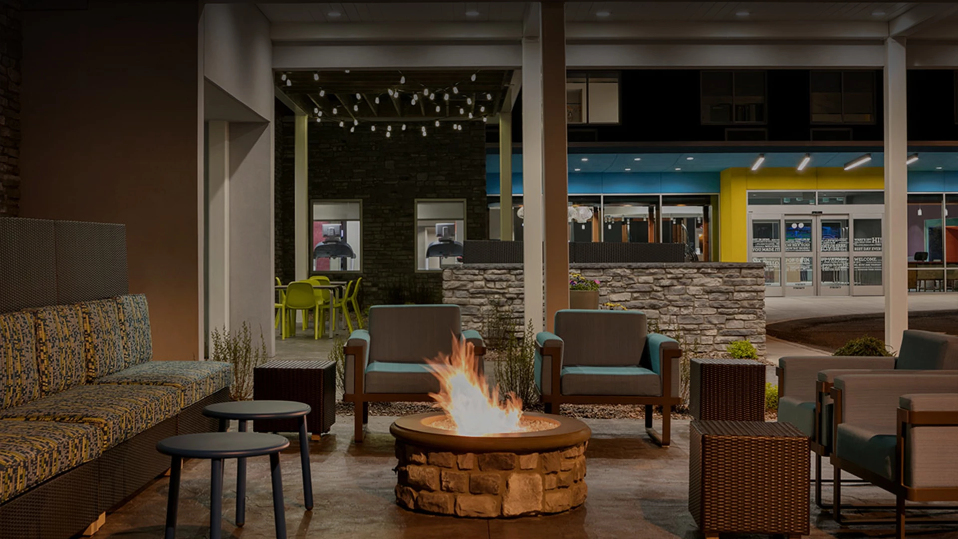 a fire pit with chairs and tables in front of a building