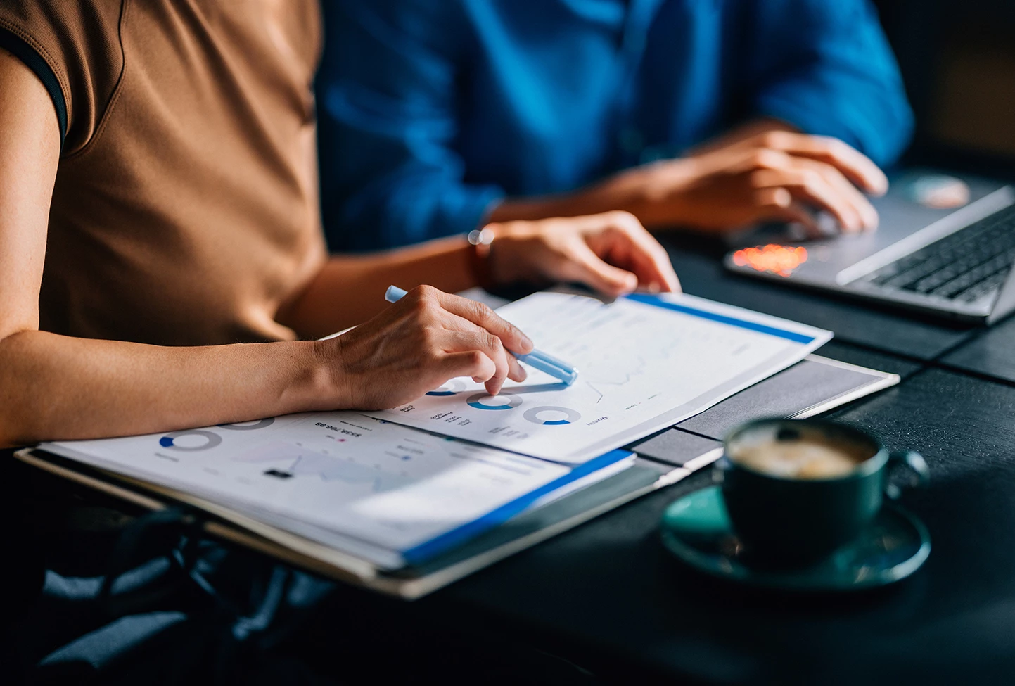 a person holding a pen and looking at a graph on paper