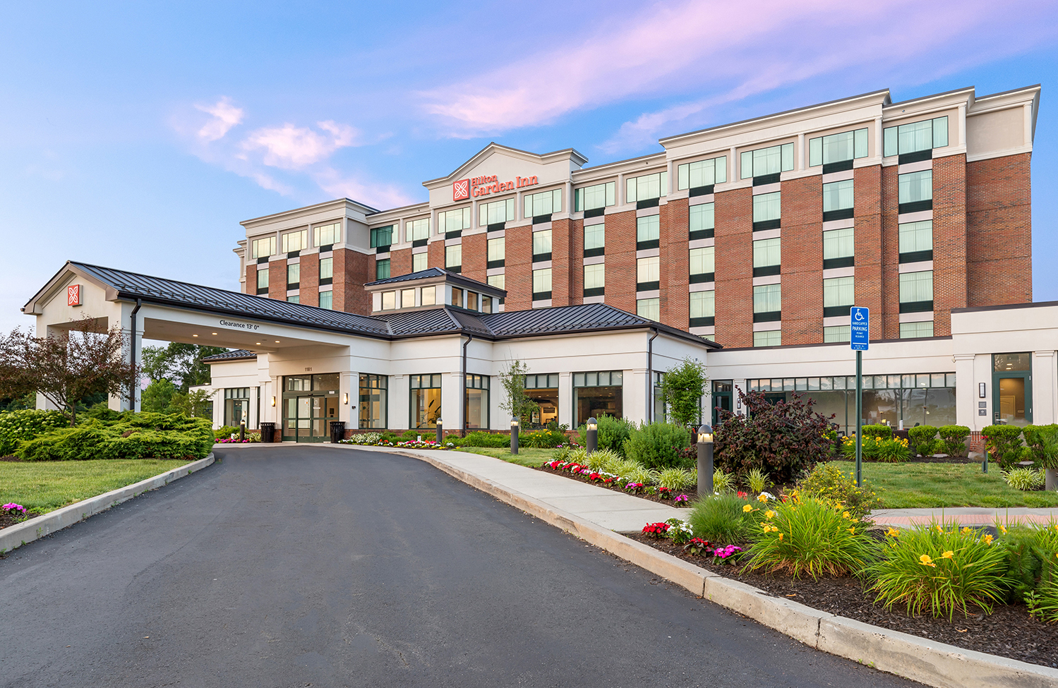 a large building with a driveway and flowers
