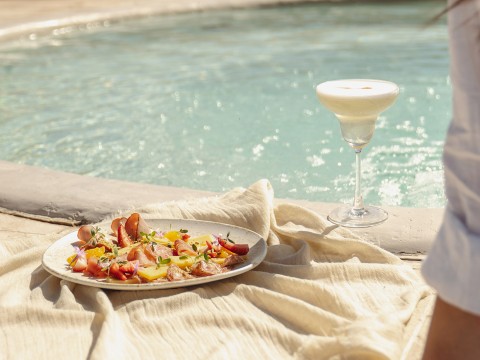 a plate of food and a drink next to a pool
