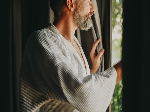 a man in a robe looking out a window