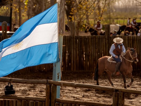 a man riding a horse in a fenced in area with a flag