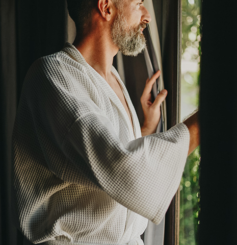 a man in a robe looking out a window