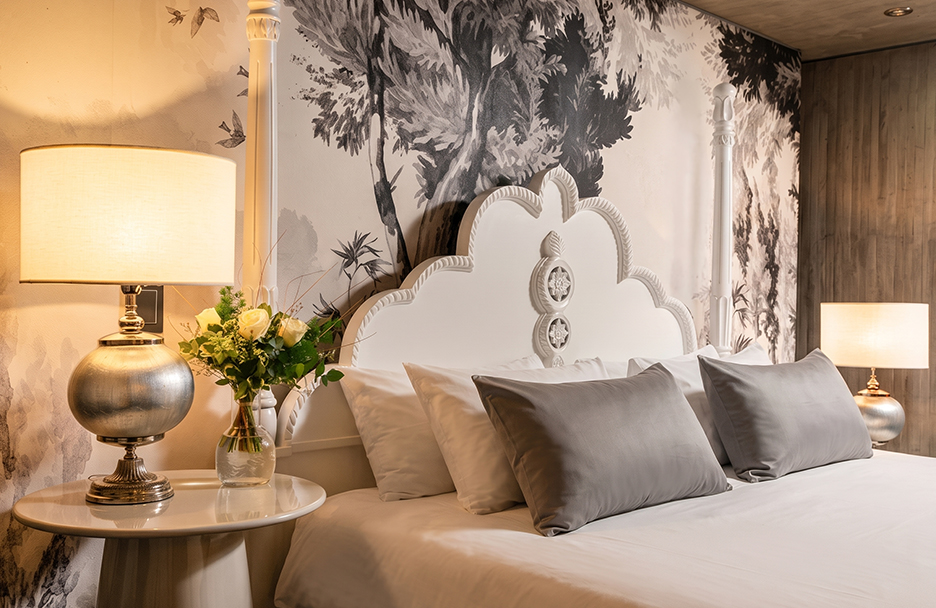 a bed with pillows and a vase of flowers