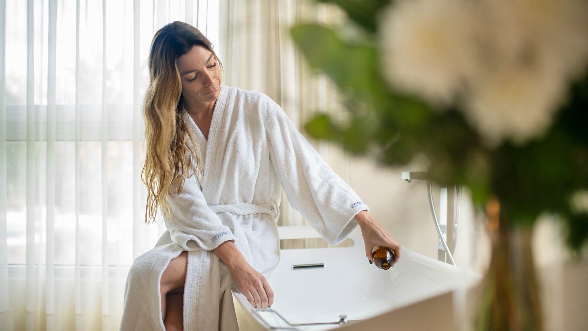 a woman in a bathrobe sitting on a bathtub