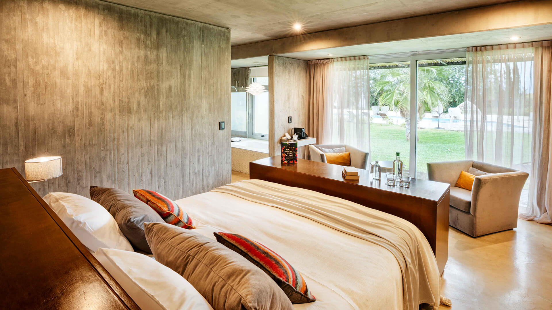 a bed with pillows and a desk in a room with a glass door