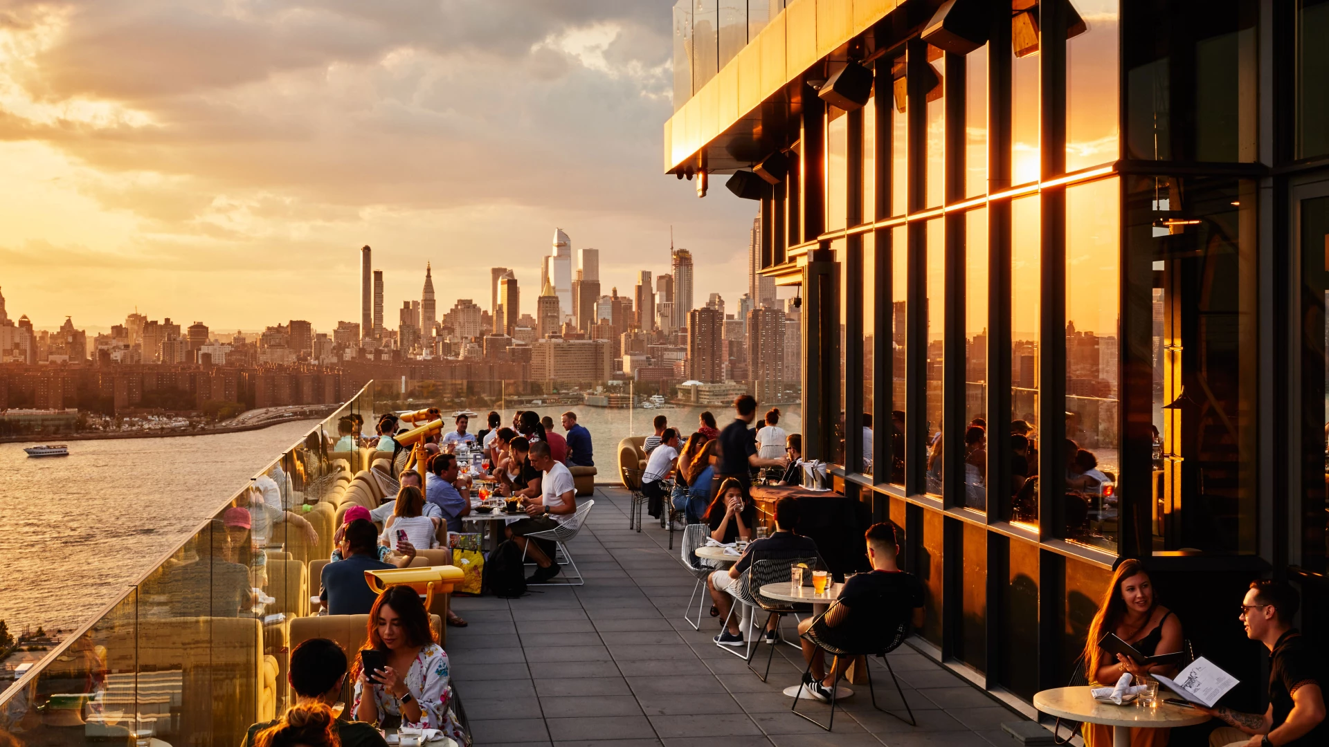 a group of people sitting at tables on a rooftop overlooking a city