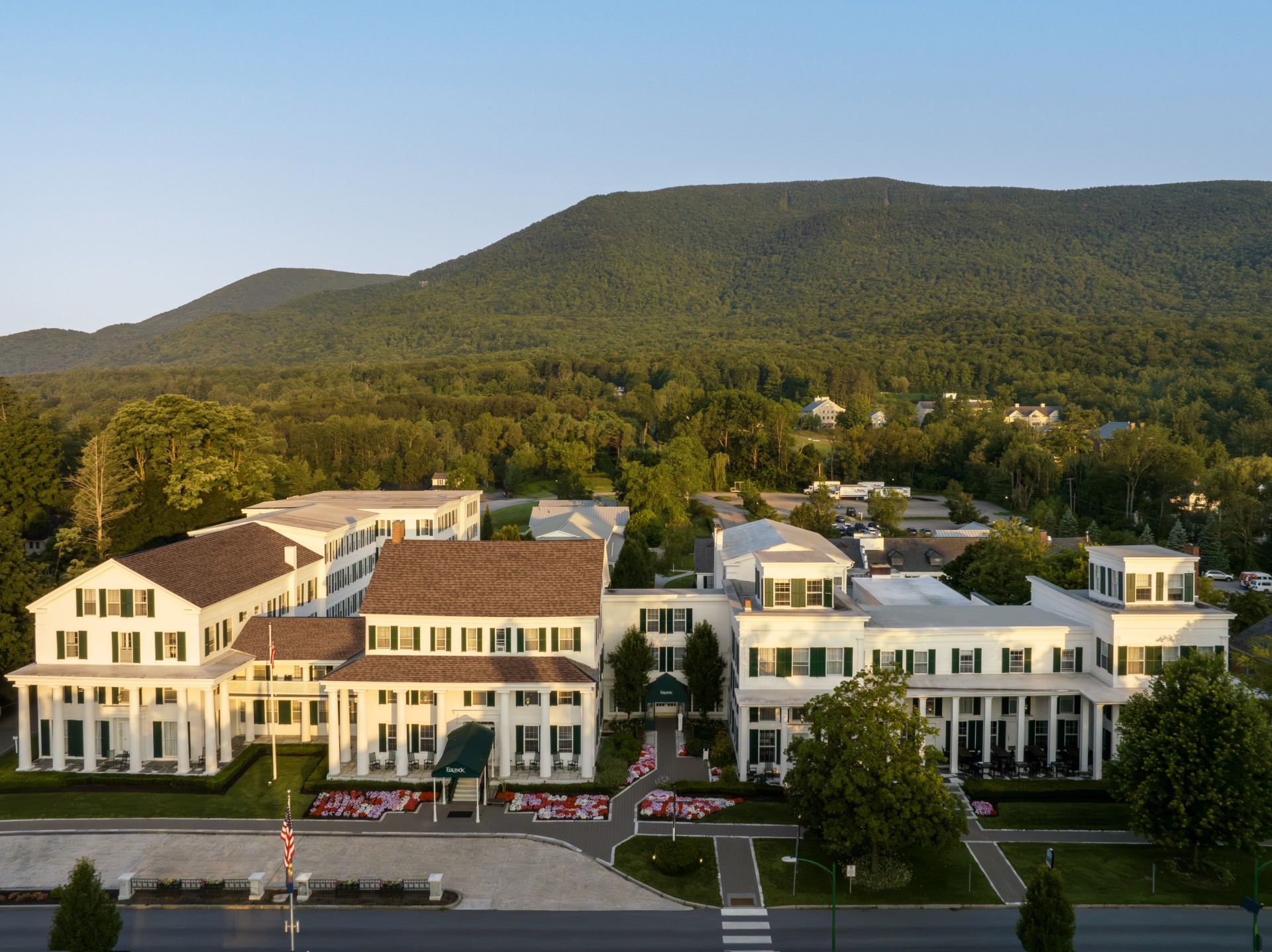 a large white building with trees and mountains in the background
