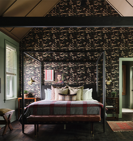 a bed in a large bedroom with high ceilings and black patterned wallpaper